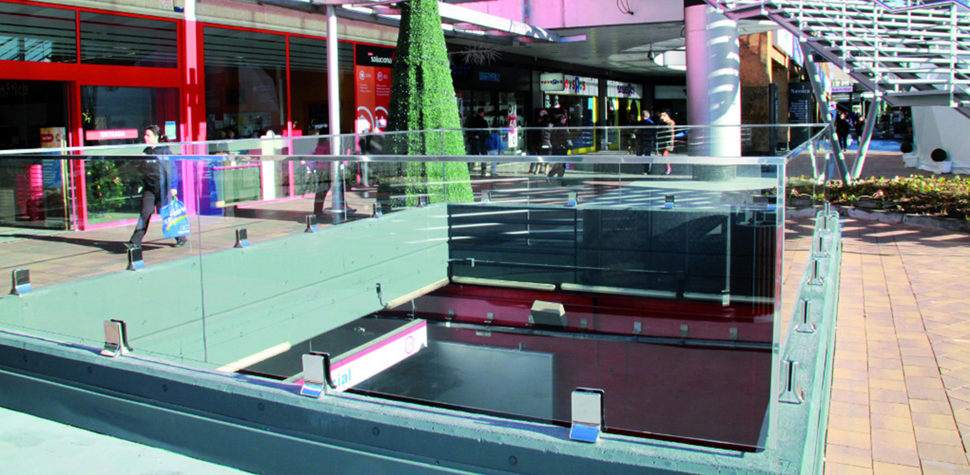Typology: Nassica Shopping Center  Materials: Stainless Steel  Location: Madrid - Spain    The project involved the construction of glass and steel protection elements for the large space town in front of the shopping center. The IAM Design Chameleon Glass System was used to close the stairs leading to the basement floors and the shafts, which, with its design, qualifies the aesthetic impact. The large staircase leading to the first level was made of iron with parapets in satin stainless steel with horizontal rods.